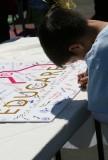 A child signs one of the three commemorative posters.